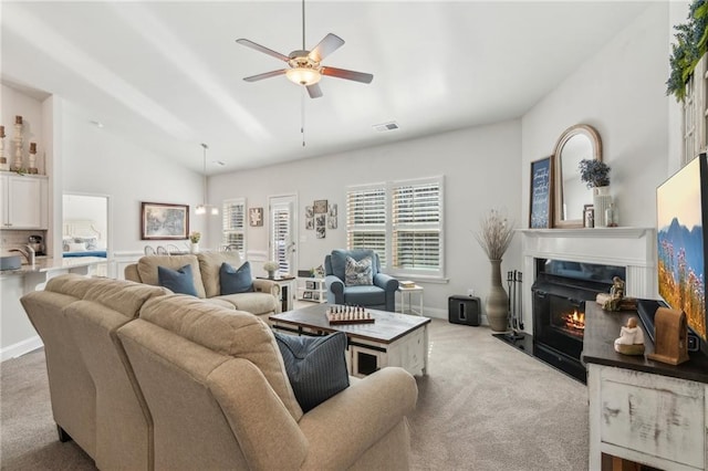 carpeted living room featuring visible vents, a glass covered fireplace, baseboards, ceiling fan, and vaulted ceiling