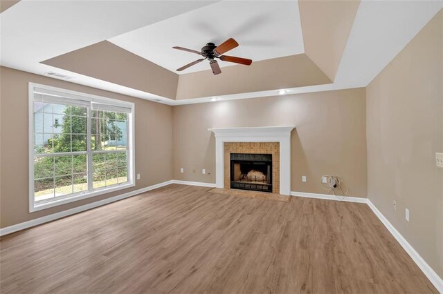 5705 Cannonero Dr, Alpharetta, GA 30005 - unfurnished living room featuring a raised ceiling, light wood-style flooring, a ceiling fan, and a fireplace