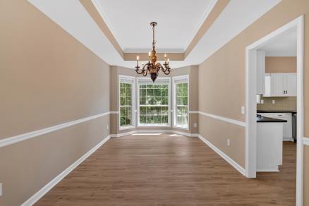 5705 Cannonero Dr, Alpharetta, GA 30005 - unfurnished dining area with a chandelier, a tray ceiling, and wood finished floors