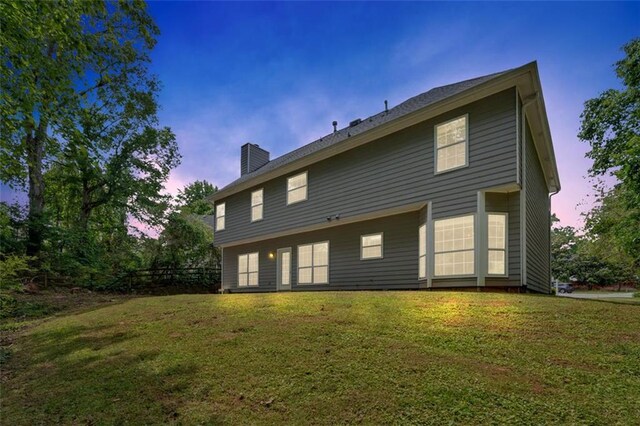 5705 Cannonero Dr, Alpharetta, GA 30005 - back of house at dusk featuring a chimney and a yard