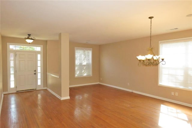 foyer with an inviting chandelier, hardwood / wood-style floors, and a healthy amount of sunlight