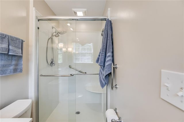 bathroom with a shower with door and toilet