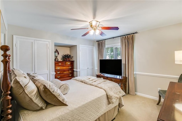 bedroom featuring ceiling fan, light carpet, and two closets