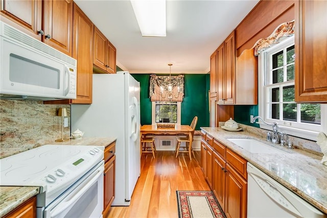 kitchen featuring decorative light fixtures, sink, white appliances, an inviting chandelier, and light hardwood / wood-style flooring