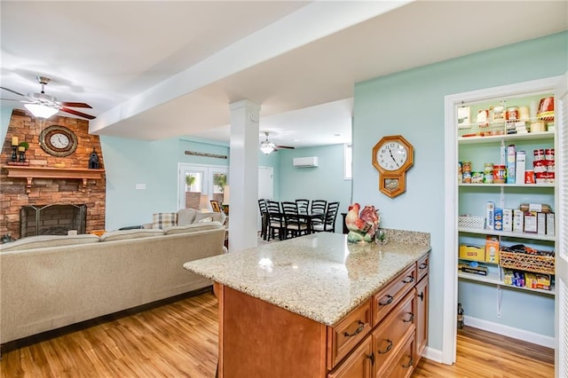 kitchen with light stone counters, a fireplace, light hardwood / wood-style flooring, and an AC wall unit