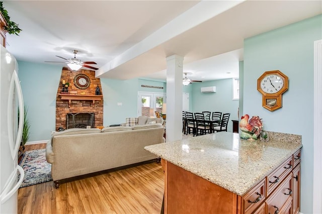 kitchen featuring light hardwood / wood-style flooring, a fireplace, light stone countertops, an AC wall unit, and white fridge