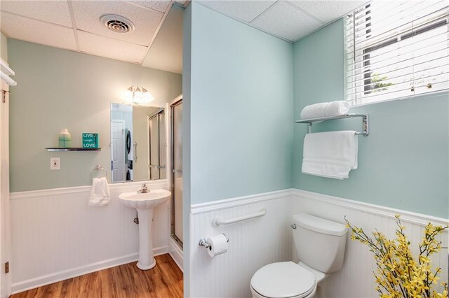 bathroom featuring hardwood / wood-style flooring, a shower with door, a drop ceiling, and toilet