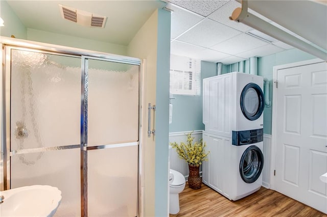 bathroom with stacked washer / drying machine, sink, a paneled ceiling, wood-type flooring, and a shower with door