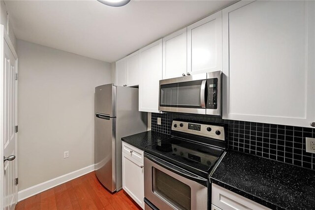 230 E Ponce De Leon Ave Unit 314, Decatur, GA 30030 - kitchen with appliances with stainless steel finishes, dark countertops, white cabinets, backsplash, and light wood-style flooring
