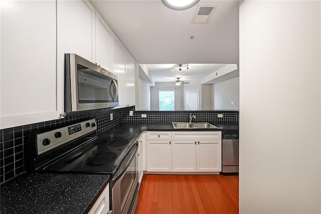 kitchen featuring tasteful backsplash, sink, white cabinetry, light hardwood / wood-style flooring, and stainless steel appliances