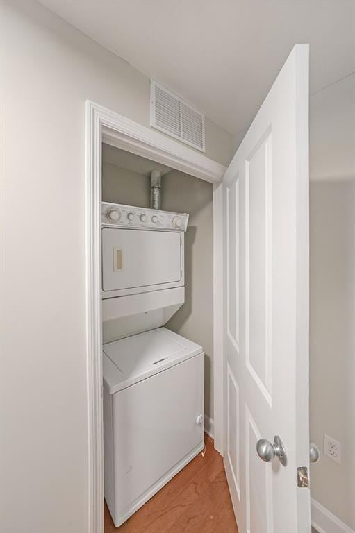 washroom with light wood-type flooring and stacked washer and clothes dryer