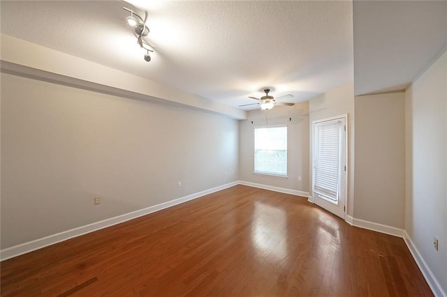 empty room with ceiling fan, dark wood-type flooring, and a textured ceiling