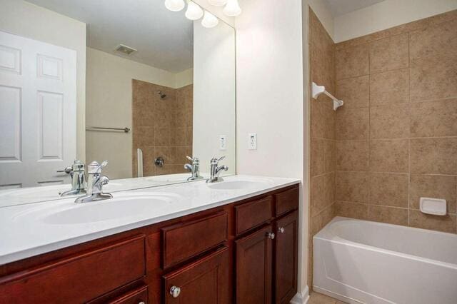 bathroom featuring tiled shower / bath and vanity