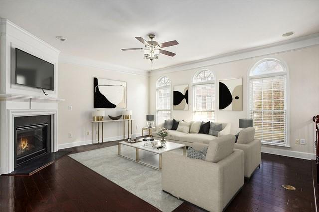 living room with ornamental molding, dark wood-type flooring, and ceiling fan