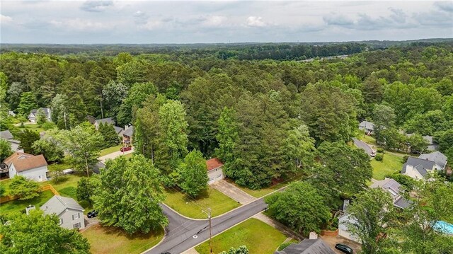 aerial view of property's location featuring a forest and nearby suburban area