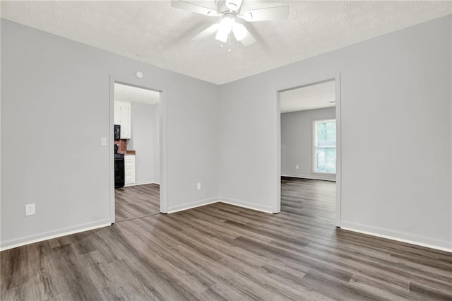 empty room featuring a ceiling fan, wood finished floors, a textured ceiling, and baseboards
