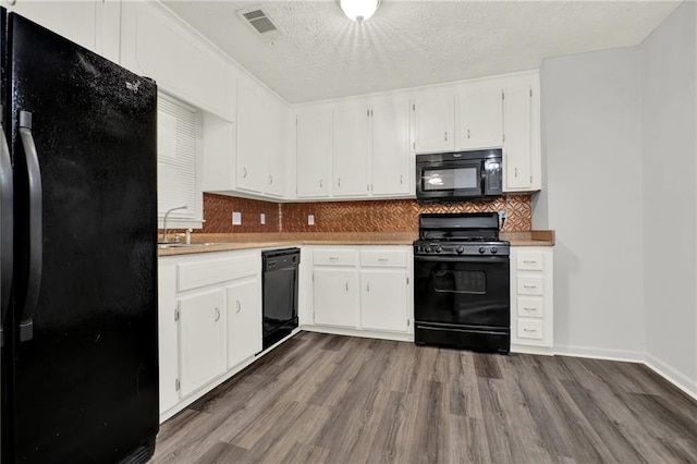 kitchen with black appliances, dark wood-type flooring, white cabinets, tasteful backsplash, and a textured ceiling