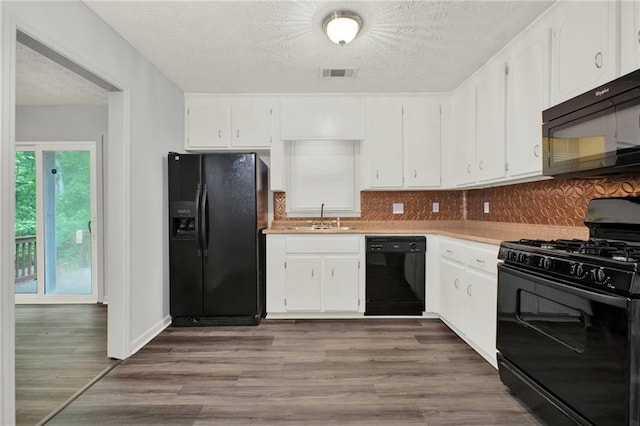 kitchen with black appliances, white cabinetry, a sink, backsplash, and a textured ceiling