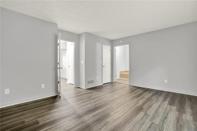 empty room featuring dark wood-type flooring, baseboards, and a textured ceiling