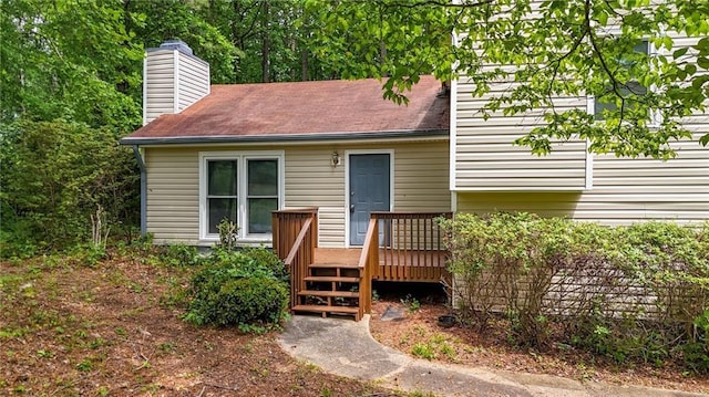 rear view of house featuring a deck and a chimney