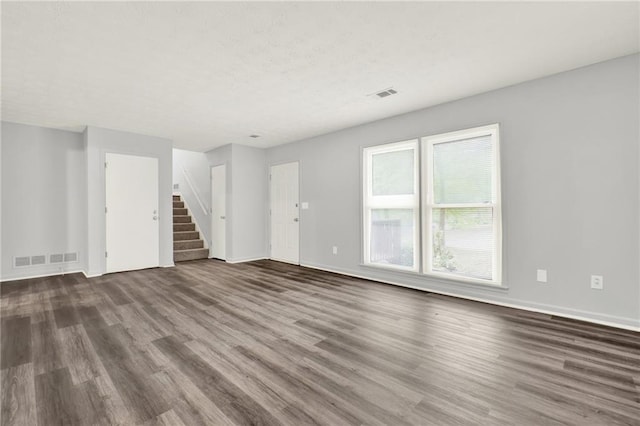 unfurnished living room with wood finished floors, stairway, and baseboards