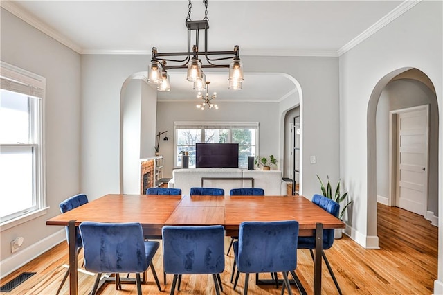 dining room with visible vents, baseboards, light wood-style floors, and ornamental molding