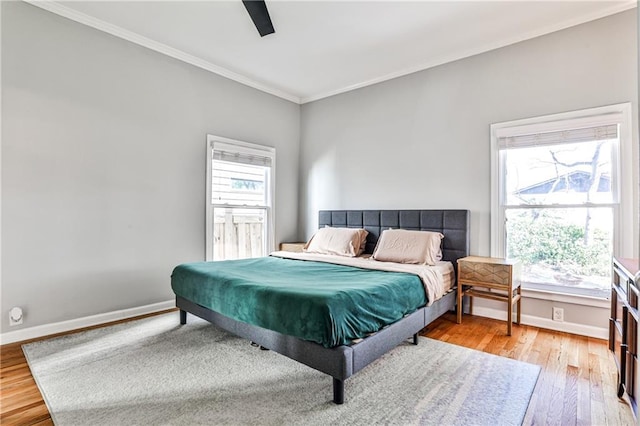 bedroom with multiple windows, baseboards, and wood finished floors