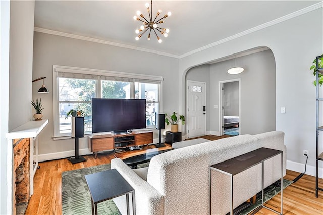 living area featuring baseboards, arched walkways, wood finished floors, and crown molding