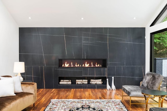 4070 Whitewater Creek Rd, Atlanta, GA 30327 - sitting room with tile walls, an accent wall, wood finished floors, a warm lit fireplace, and recessed lighting