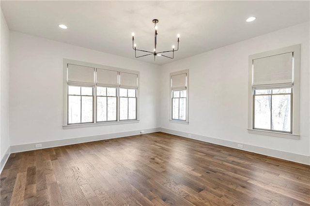 spare room featuring dark hardwood / wood-style flooring and an inviting chandelier