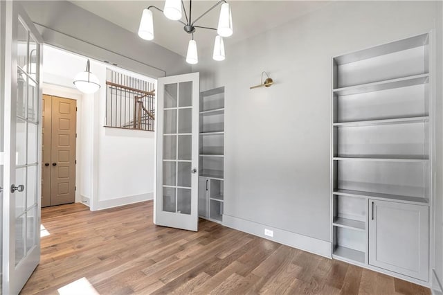 unfurnished room featuring french doors, hardwood / wood-style floors, and a notable chandelier