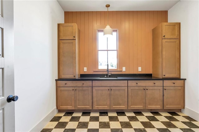 kitchen with pendant lighting, sink, and wood walls