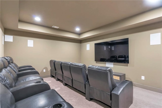 cinema room featuring a raised ceiling and light carpet