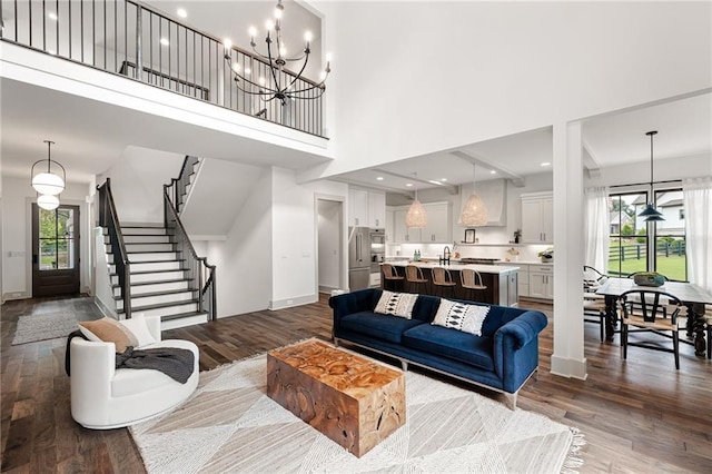 living room with a chandelier, dark hardwood / wood-style floors, a healthy amount of sunlight, and a high ceiling