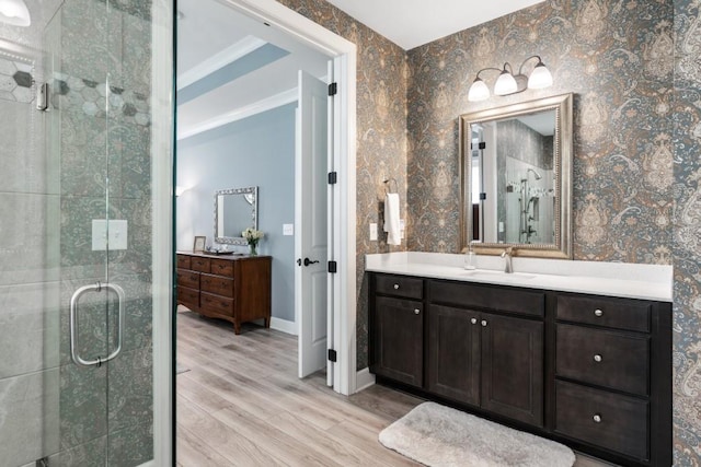 310 Chatuge Dr, Hoschton, GA 30548 - full bathroom featuring wood finished floors, a stall shower, two vanities, wallpapered walls, and baseboards