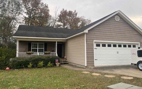 single story home with a front lawn, a porch, and a garage