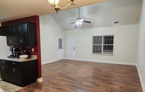 interior space with a textured ceiling, lofted ceiling, ceiling fan, and wood-type flooring