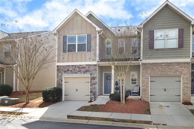 townhome / multi-family property featuring a garage, concrete driveway, brick siding, and board and batten siding