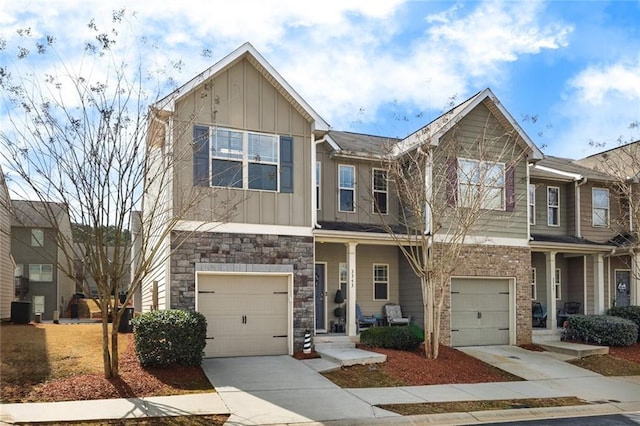 townhome / multi-family property with an attached garage, central air condition unit, brick siding, concrete driveway, and board and batten siding