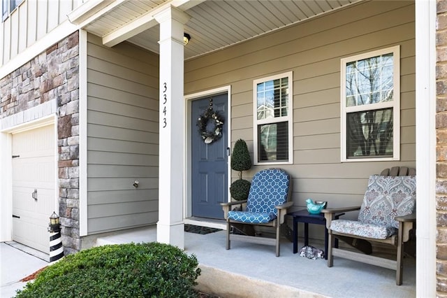 property entrance with a garage, stone siding, a porch, and board and batten siding