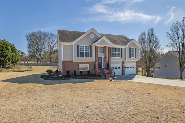 bi-level home with a garage, concrete driveway, and brick siding