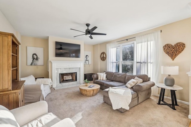 living room featuring ceiling fan, light colored carpet, baseboards, and a premium fireplace