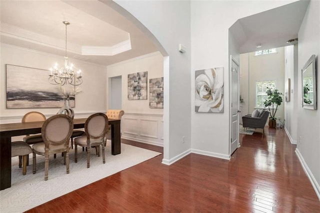 dining room with a tray ceiling, a chandelier, dark wood-type flooring, and ornamental molding