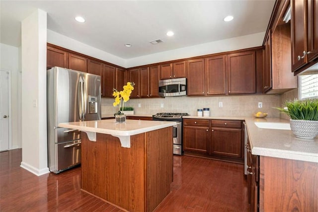 kitchen with sink, dark hardwood / wood-style floors, decorative backsplash, appliances with stainless steel finishes, and a kitchen island