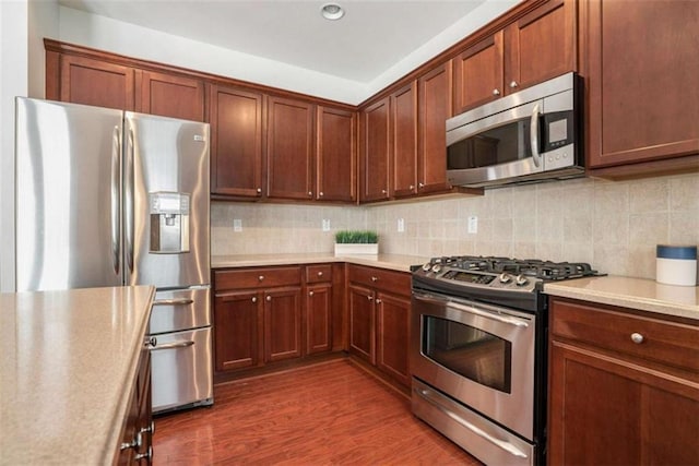 kitchen with decorative backsplash, dark wood-type flooring, and appliances with stainless steel finishes