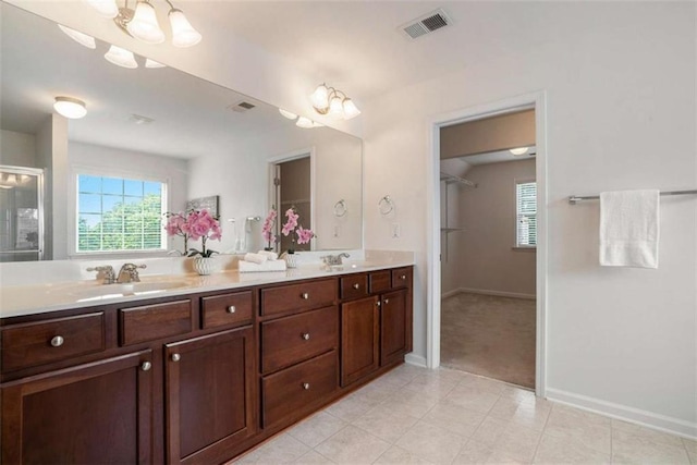 bathroom with tile patterned flooring, vanity, and an inviting chandelier