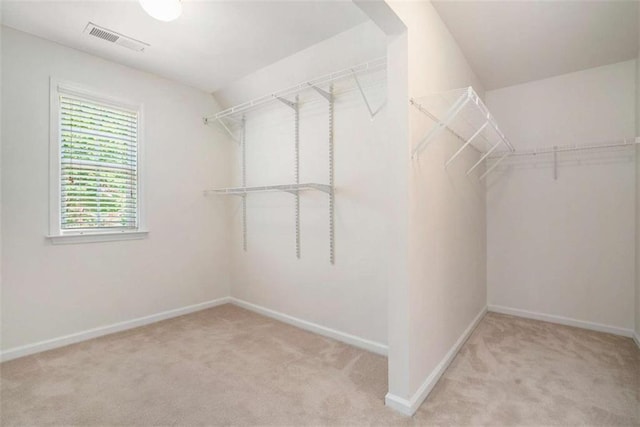 walk in closet featuring light colored carpet