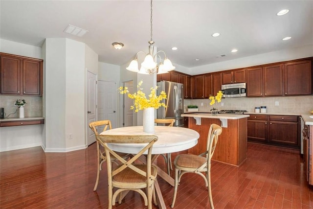 kitchen featuring pendant lighting, backsplash, stainless steel appliances, and dark hardwood / wood-style flooring