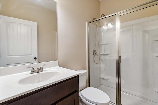 bathroom featuring toilet, a stall shower, and vanity
