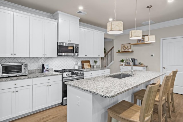 kitchen with a sink, appliances with stainless steel finishes, white cabinetry, decorative backsplash, and a toaster